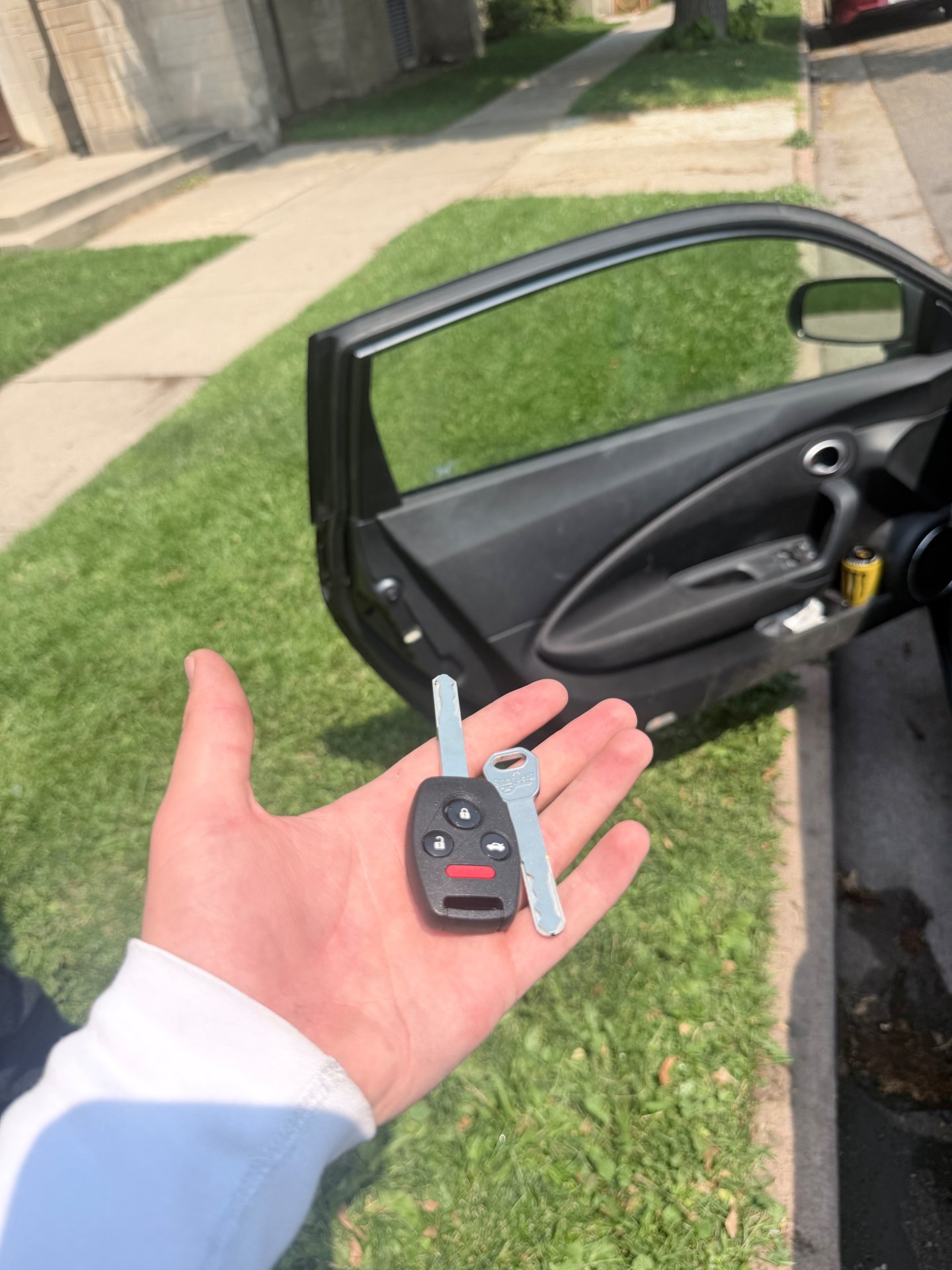 New Honda transponder remote head key and cut key blade held in hand beside an open 2012 Honda CR-Z door in Denver, Colorado