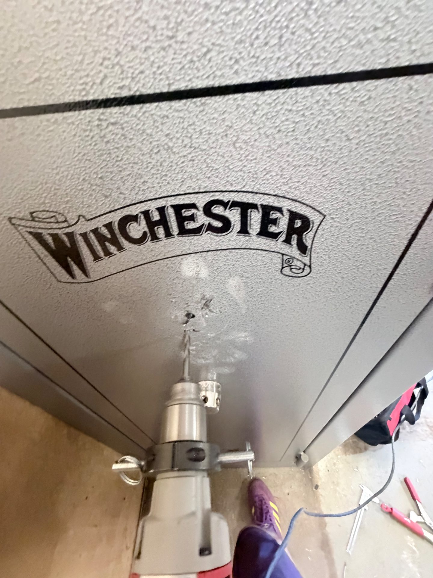 Drill rig set on the correct drill point of a Winchester gun safe during a safe opening in Morrison, Colorado