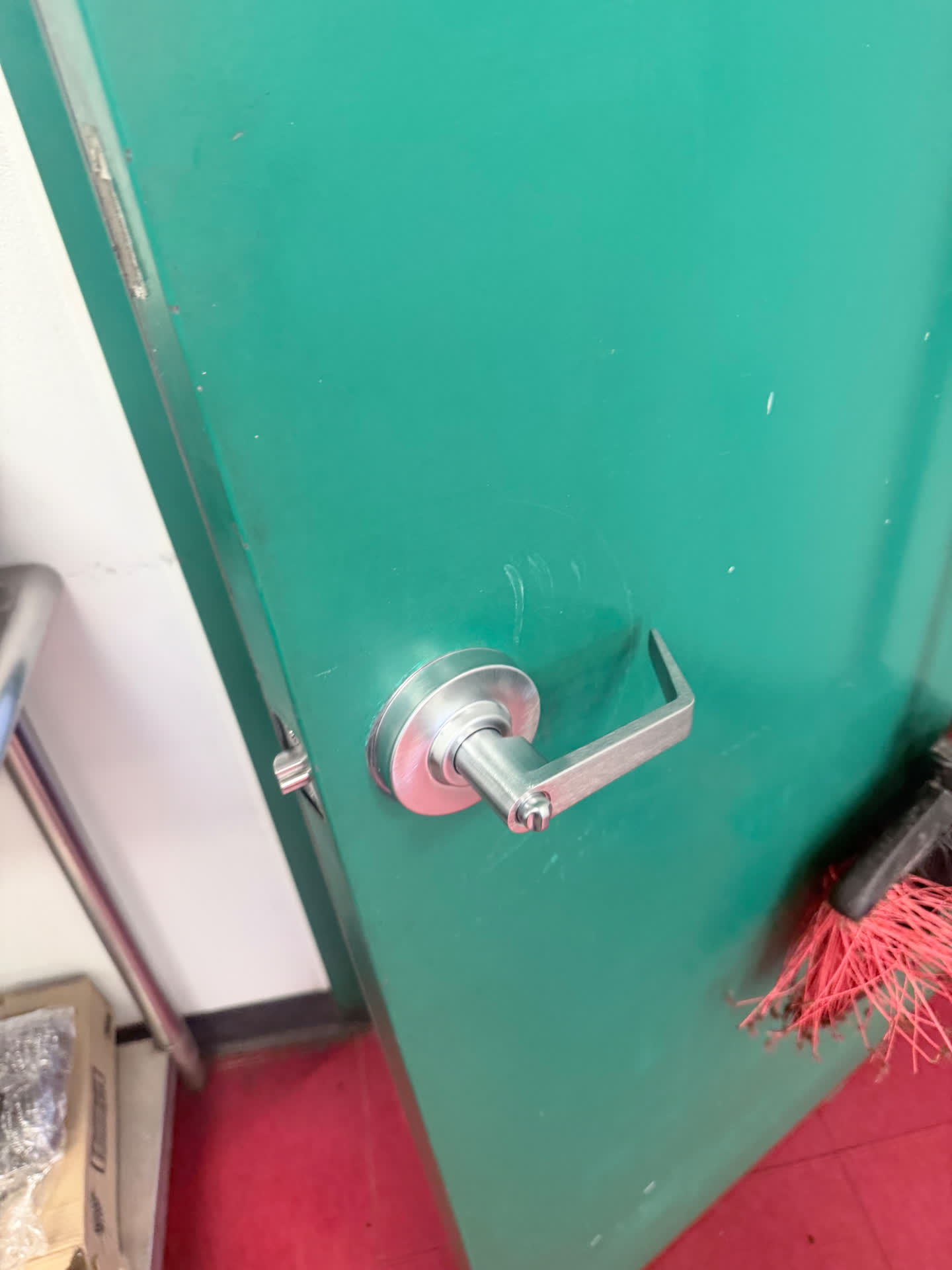 Close-up of a replacement commercial lever handle on a green interior door in Denver, Colorado