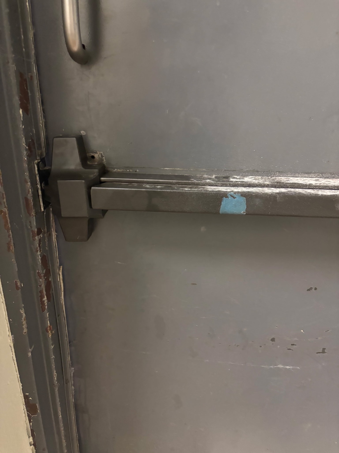 Newly installed dark commercial panic bar exit device on a steel emergency exit door in Littleton, Colorado