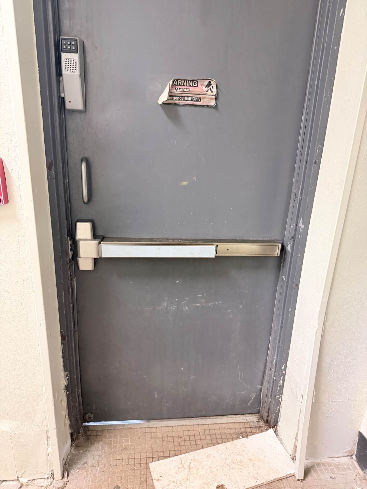 Commercial emergency exit door with the original worn panic bar before replacement in Littleton, Colorado